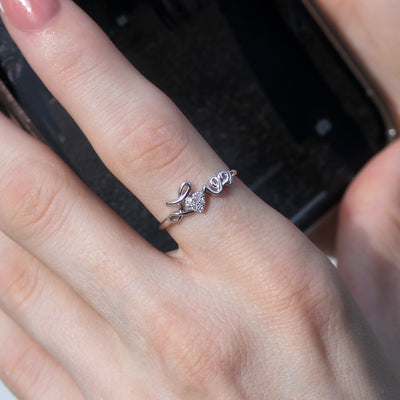 Close-up of a hand wearing a silver ring with leaf design on a blurred background