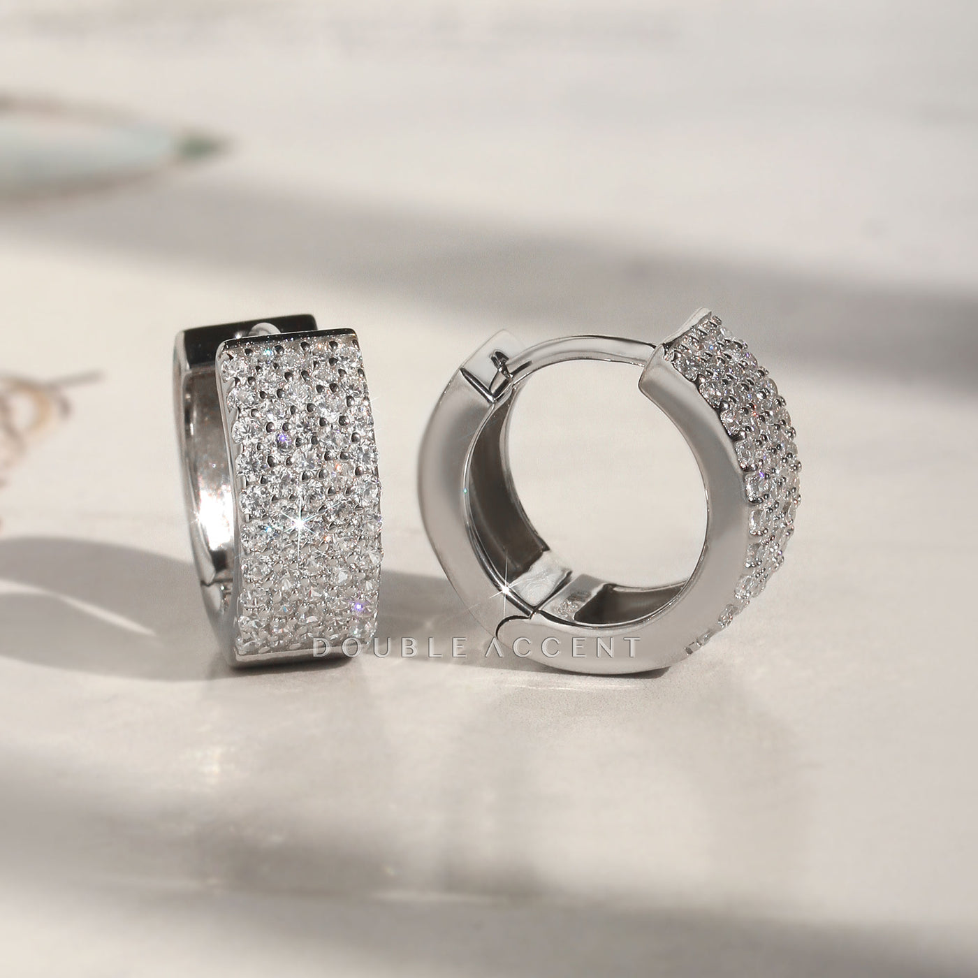Five-row pave huggie hoop earrings shown in close-up lighting