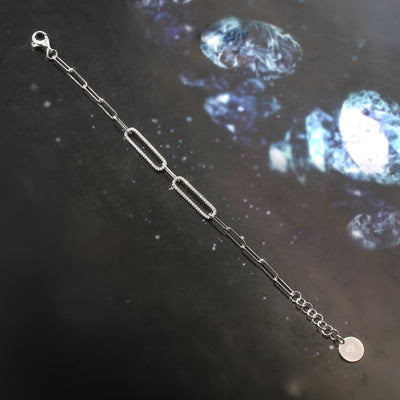 Silver bracelet on a dark surface with a celestial background