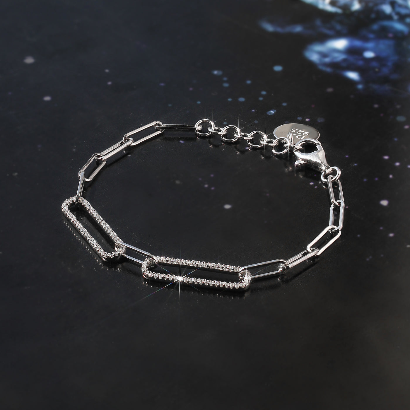Silver bracelet with chain design on a dark reflective surface
