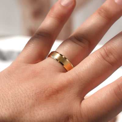 Gold ring on a person's finger with a blurred background