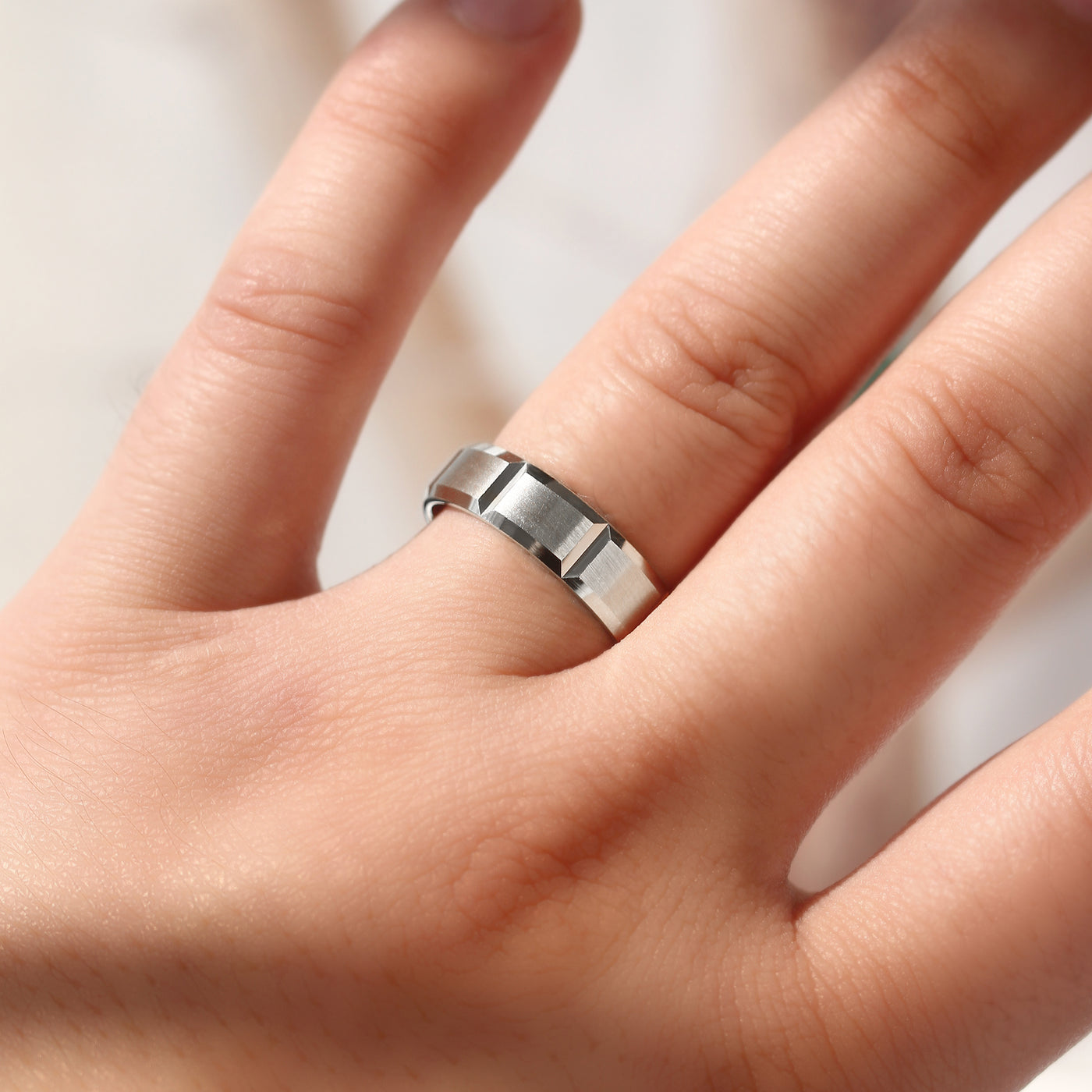 14K white gold ring on a person's finger against a neutral background