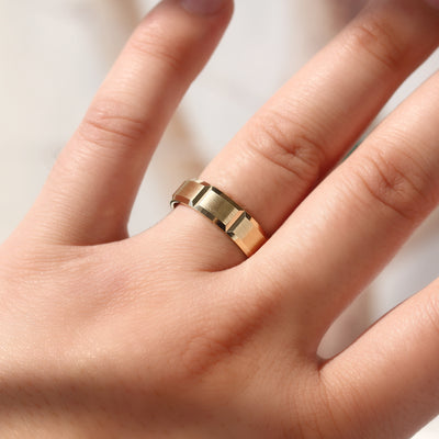 Gold ring on a person's finger against a neutral background