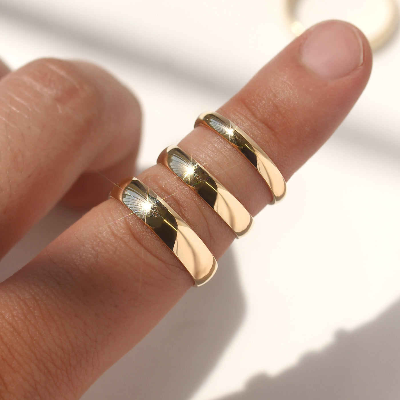 Gold rings on a finger with a neutral background