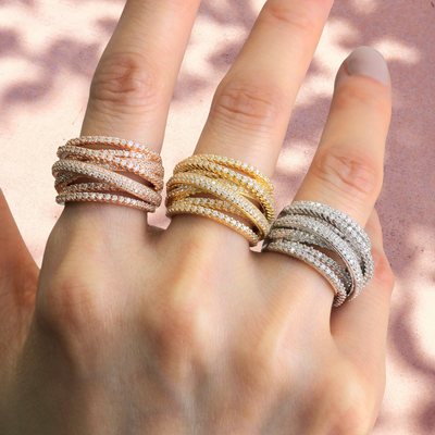 Three stacked crisscross ring on a hand with a soft pink background