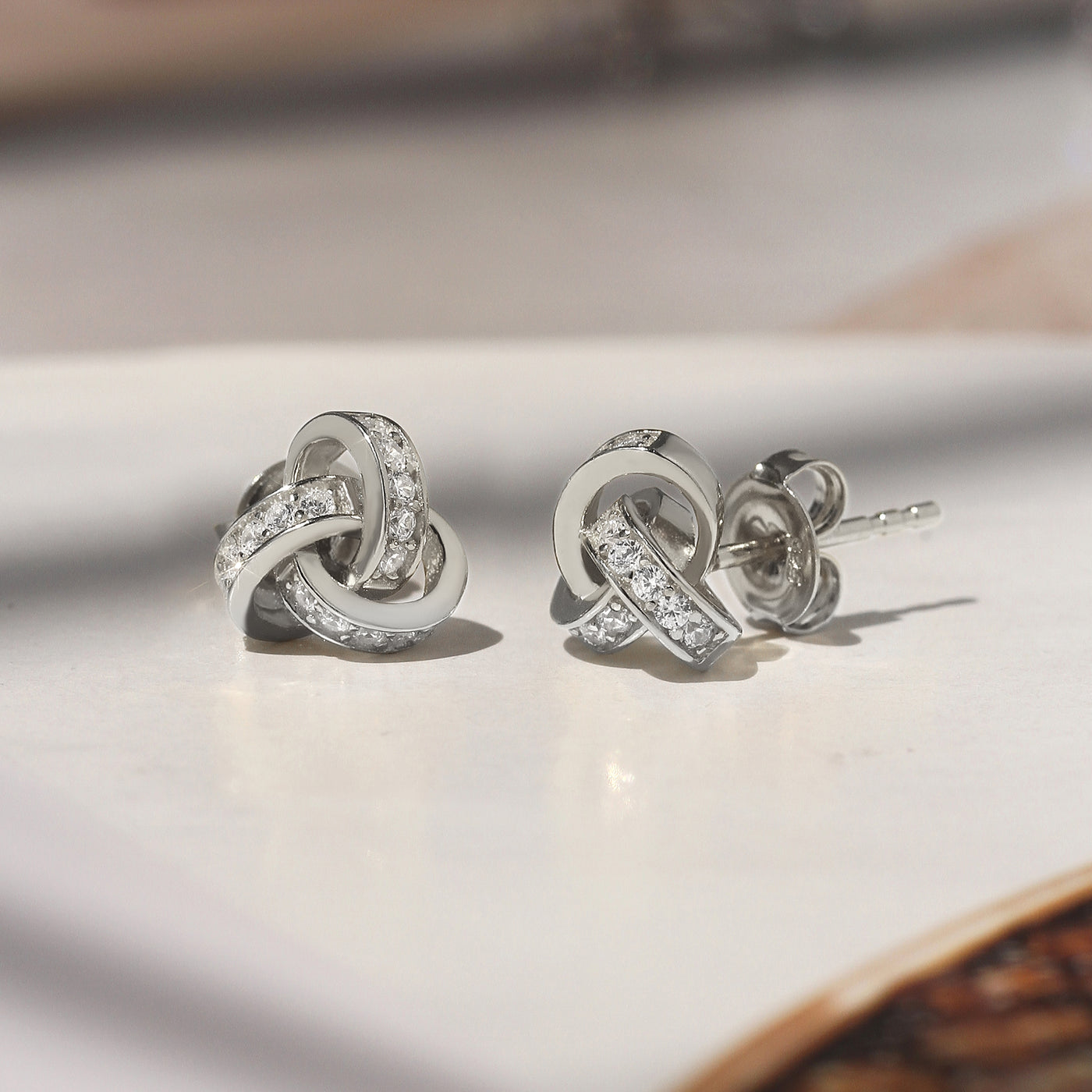 Promise Love Knot Stud Earrings in sterling silver with cubic zirconia stones, available in gold, rose gold, or rhodium finish.