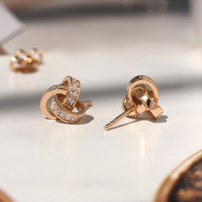 Promise Love Knot Stud Earrings in sterling silver with cubic zirconia stones, available in gold, rose gold, or rhodium finish.
