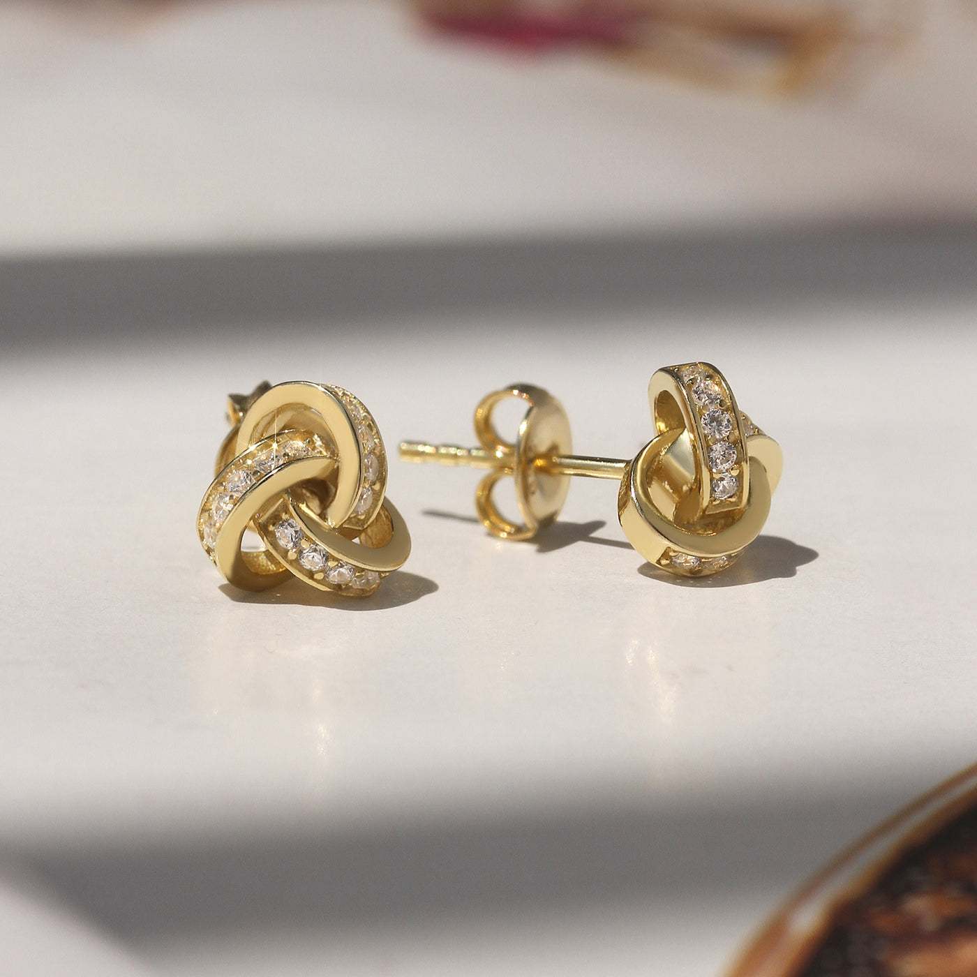 Promise Love Knot Stud Earrings in sterling silver with cubic zirconia stones, available in gold, rose gold, or rhodium finish.