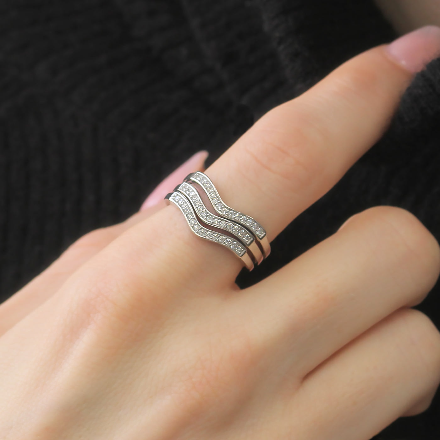 Hand wearing stacked chevron rings with various styling.