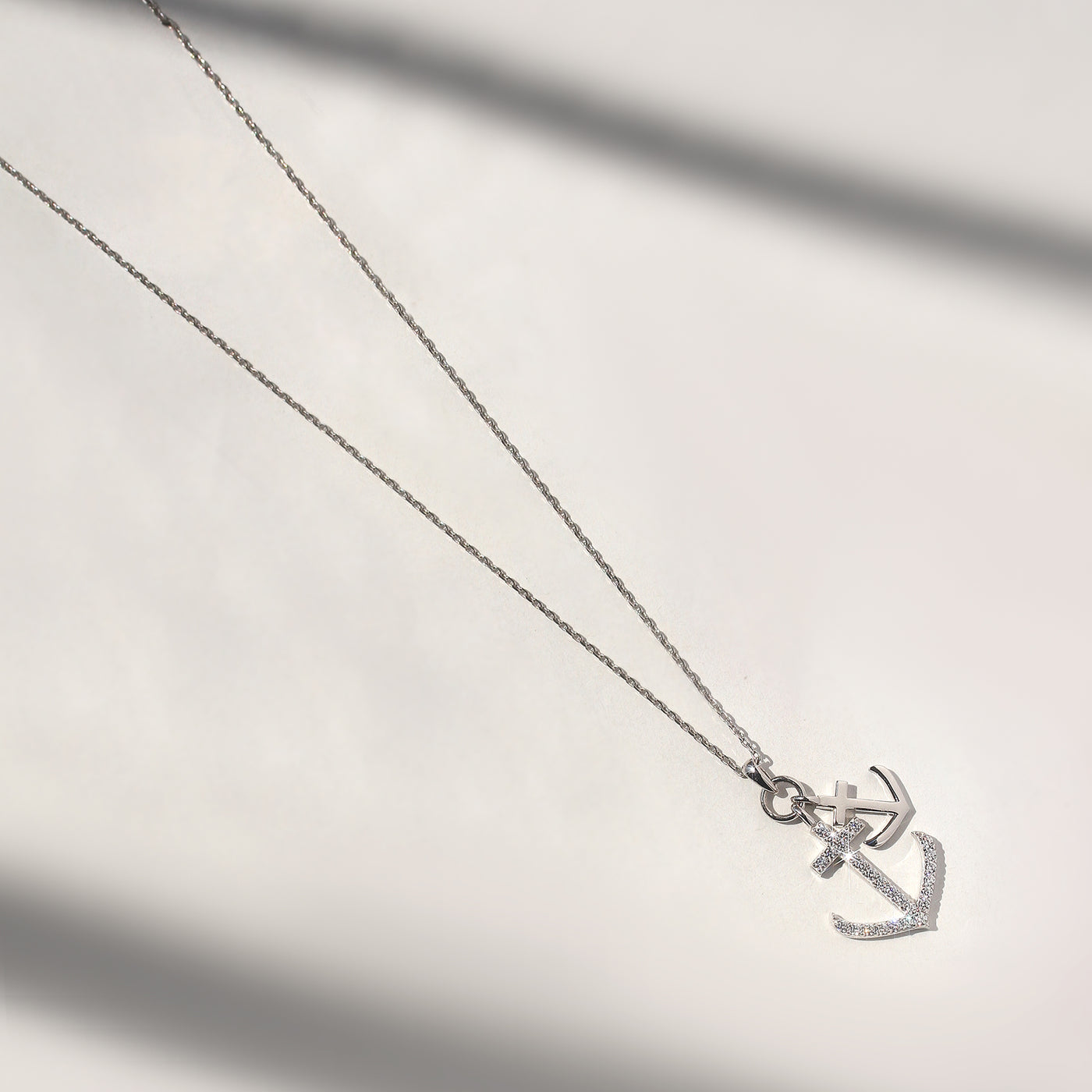Silver anchor necklace on a light gray background