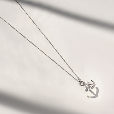 Silver anchor necklace on a light gray background