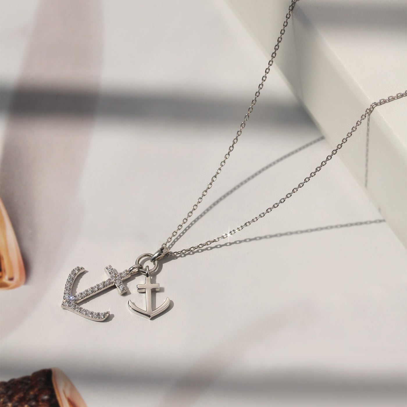 Silver necklace with anchor pendant on a soft fabric background