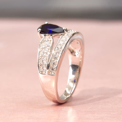 Silver ring with a blue gemstone on a pink fabric background