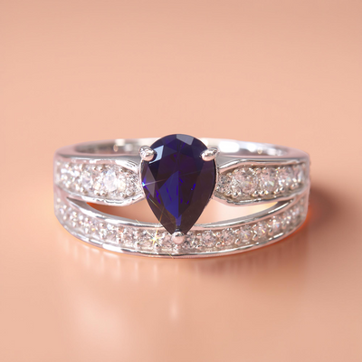 Bluebound Ring – sterling silver band featuring a natural blue spinel teardrop and two rows of white stones, representing emotional growth and rebirth.