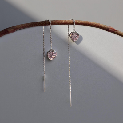 Delicate heart bezel threader earrings hanging on a branch, shown in soft natural light