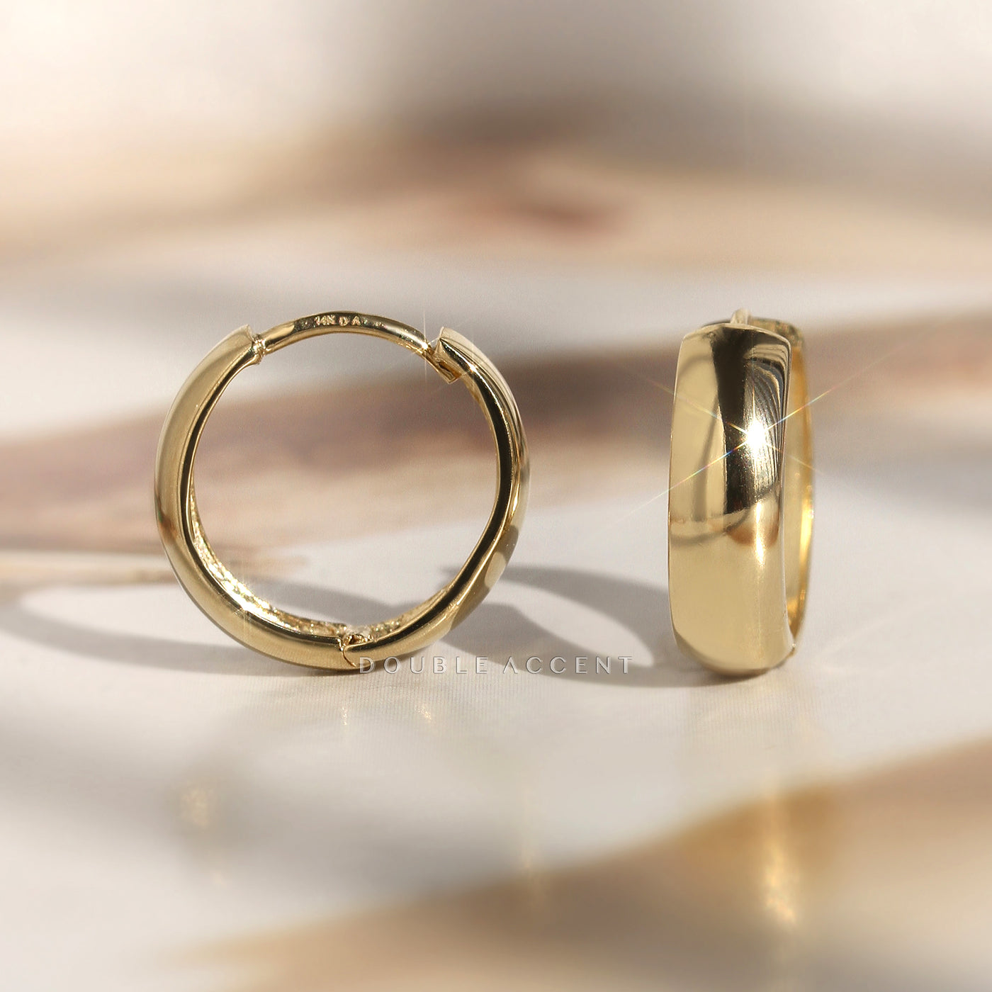 Close-up of dome-finished 14K gold huggie with click closure