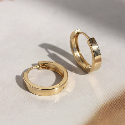 Close-up of First Shine Huggie Hoops with visible snap closure