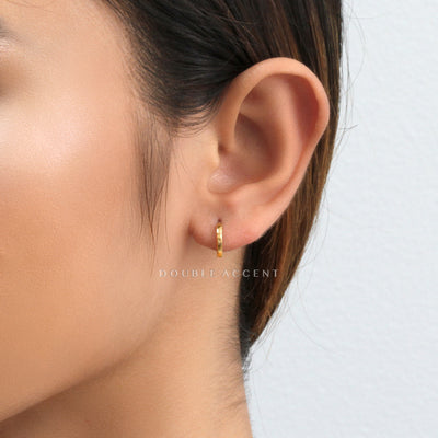 Gold hoop earring worn by a person with a neutral background