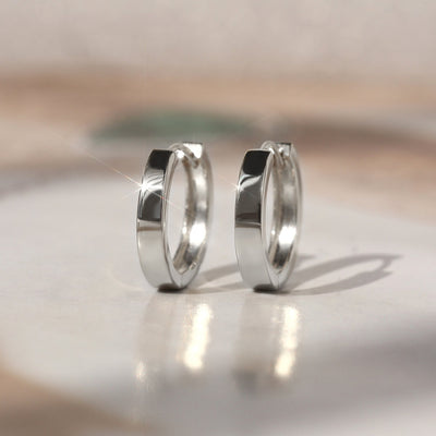 Flat-style 14K white gold huggie hoop earrings shown side by side