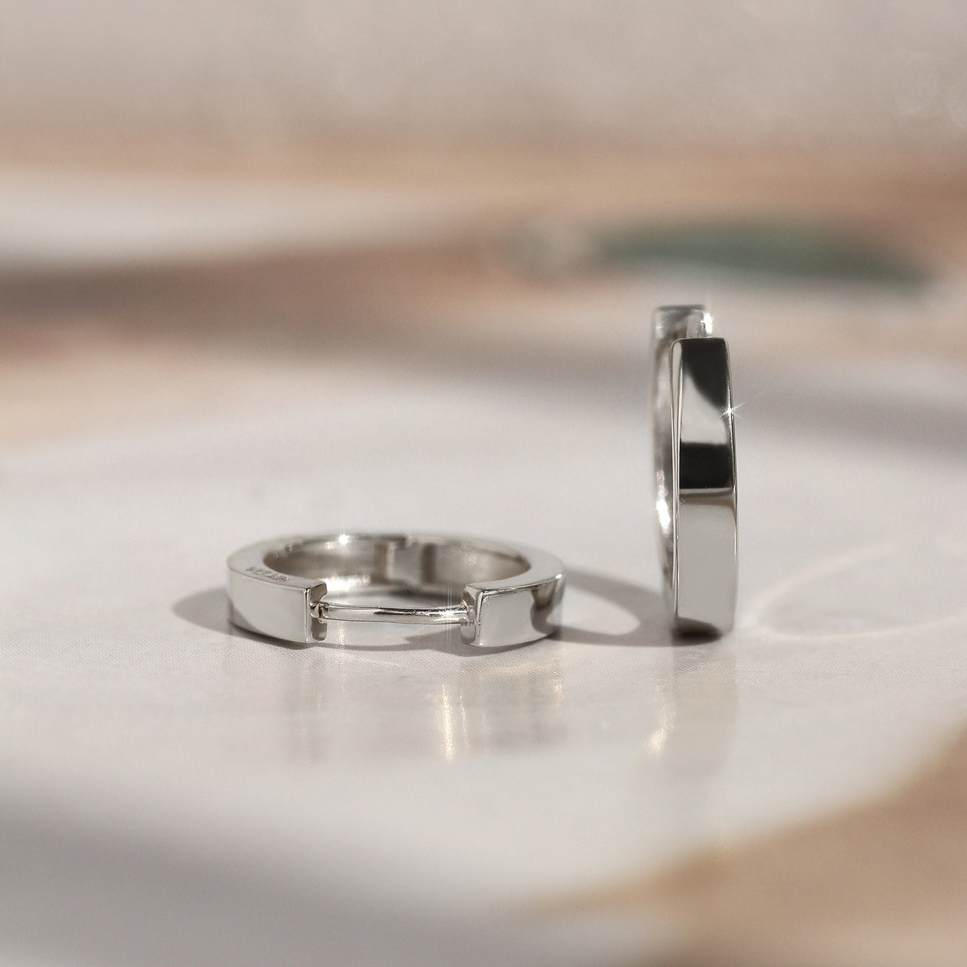 White gold First Shine Huggie Hoops softly lit for texture detail