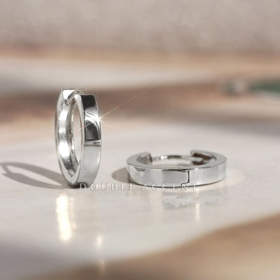 14K white gold huggie hoops on a reflective surface with 'Double Acces' branding.