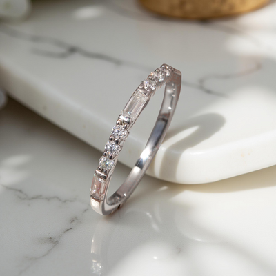 Platinum-plated sterling silver half eternity band with alternating baguette and round moissanite stones.