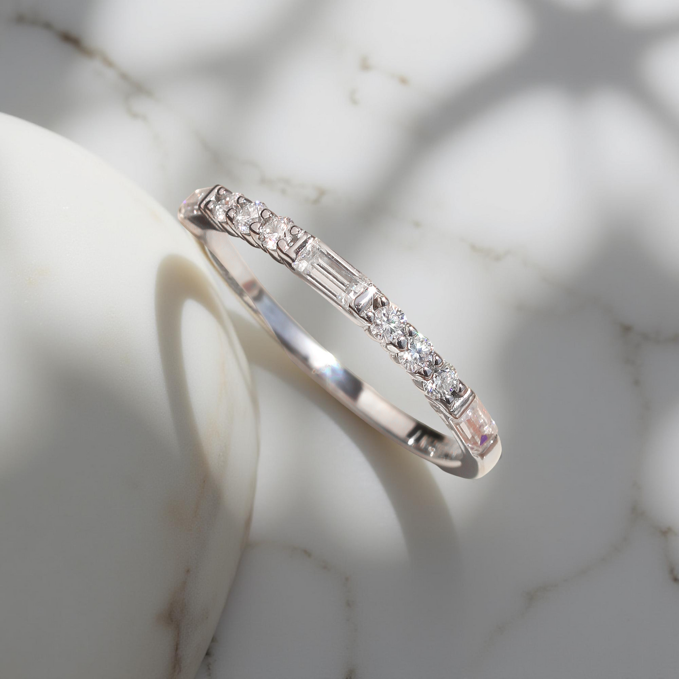 Platinum-plated sterling silver half eternity band with alternating baguette and round moissanite stones.