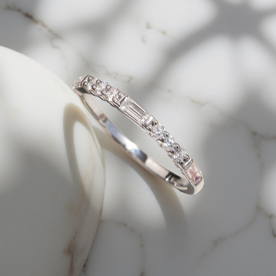 Platinum-plated sterling silver half eternity band with alternating baguette and round moissanite stones.