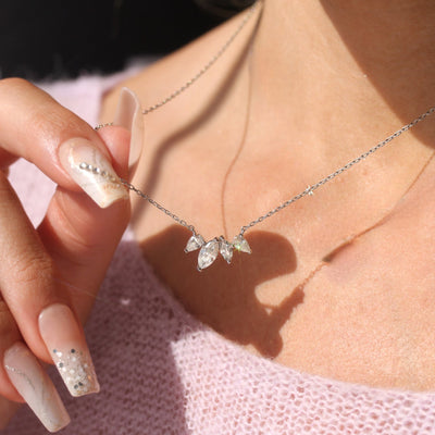 Woman holding and wearing the Still Blooming Lily Necklace — soft floral sparkle