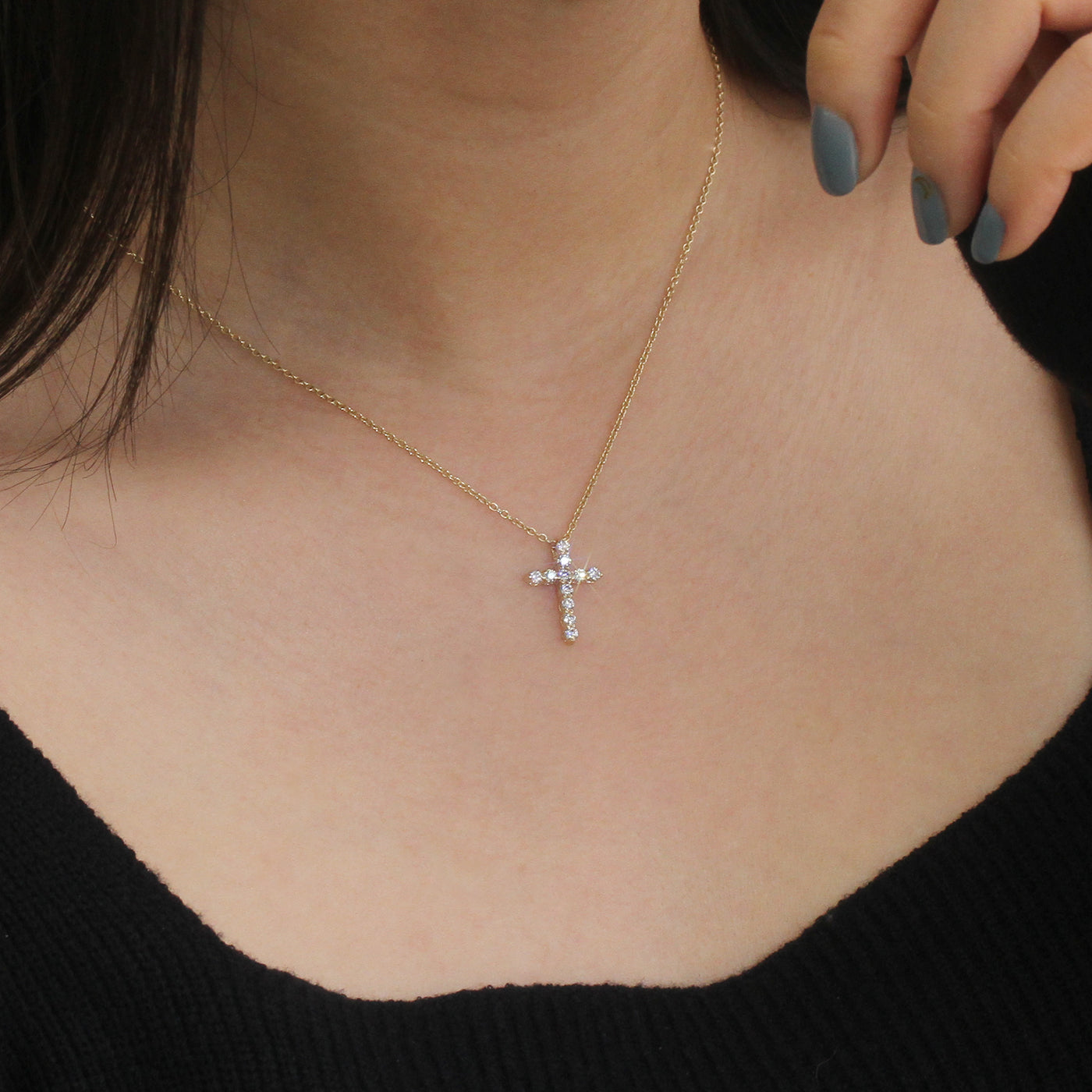 Gold necklace with a cross pendant worn by a person