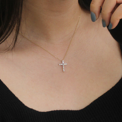 Gold necklace with a cross pendant worn by a person