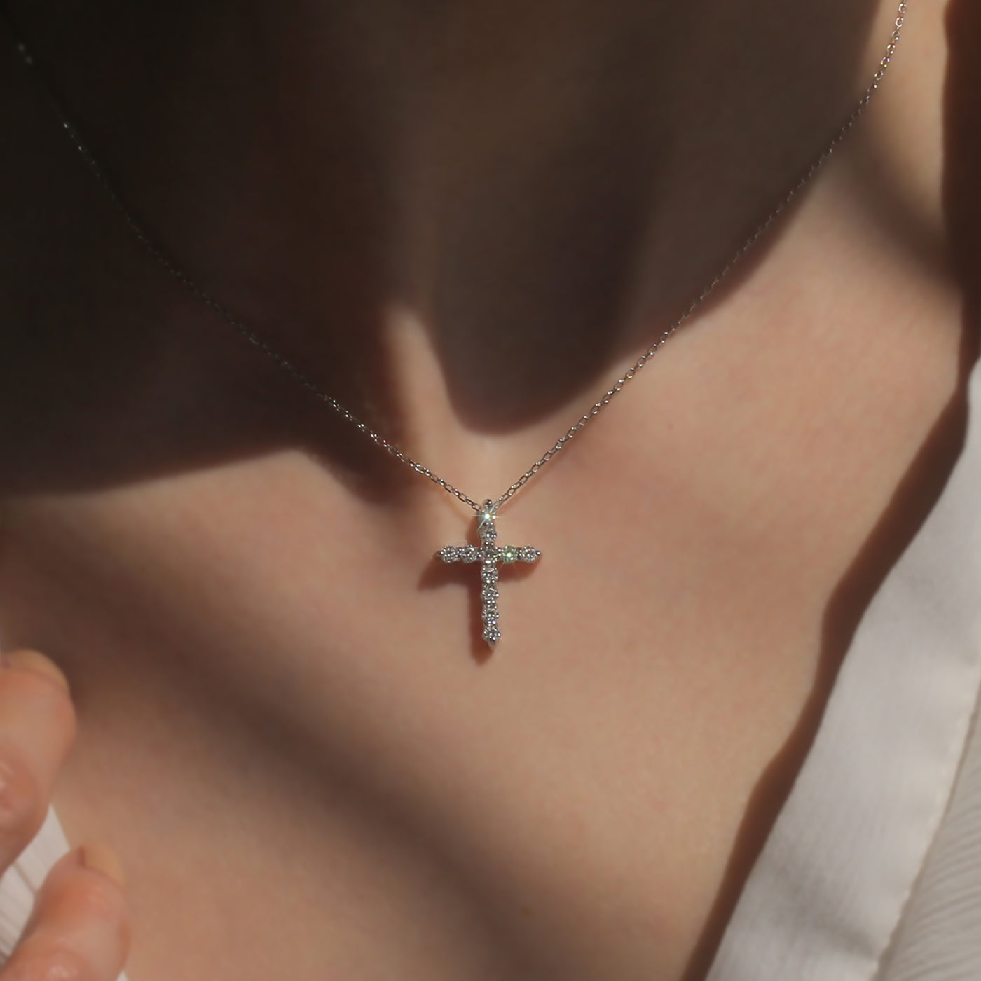 Cross-shaped necklace with diamonds on a person's neck
