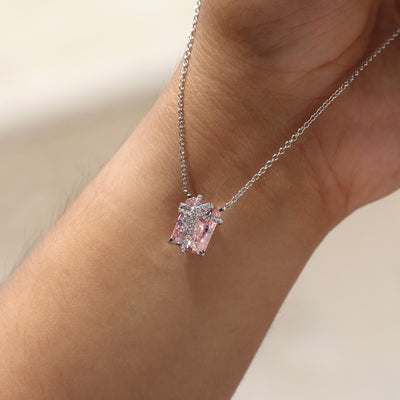 Pink gemstone necklace on a wrist against a neutral background