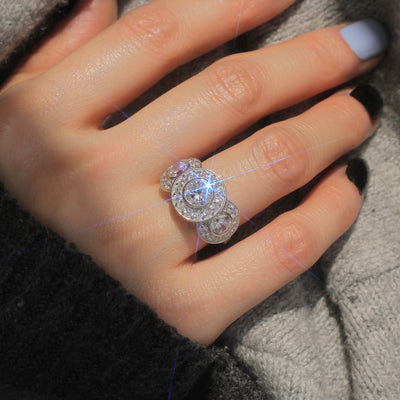 Close-up of a hand wearing a silver ring with a central diamond and two smaller diamonds on either side.