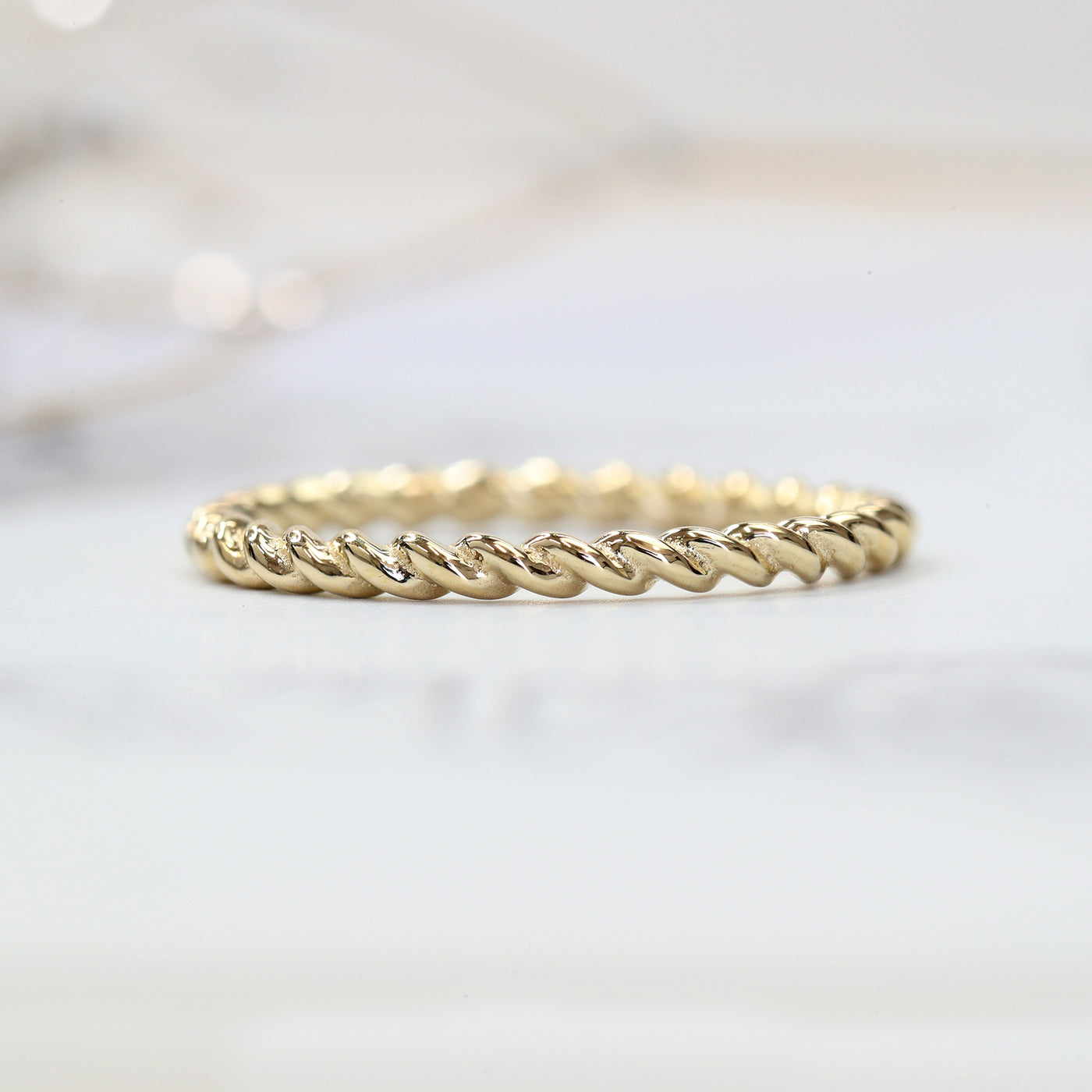 Gold twisted ring on a light gray background