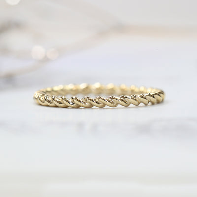 Gold twisted ring on a light gray background