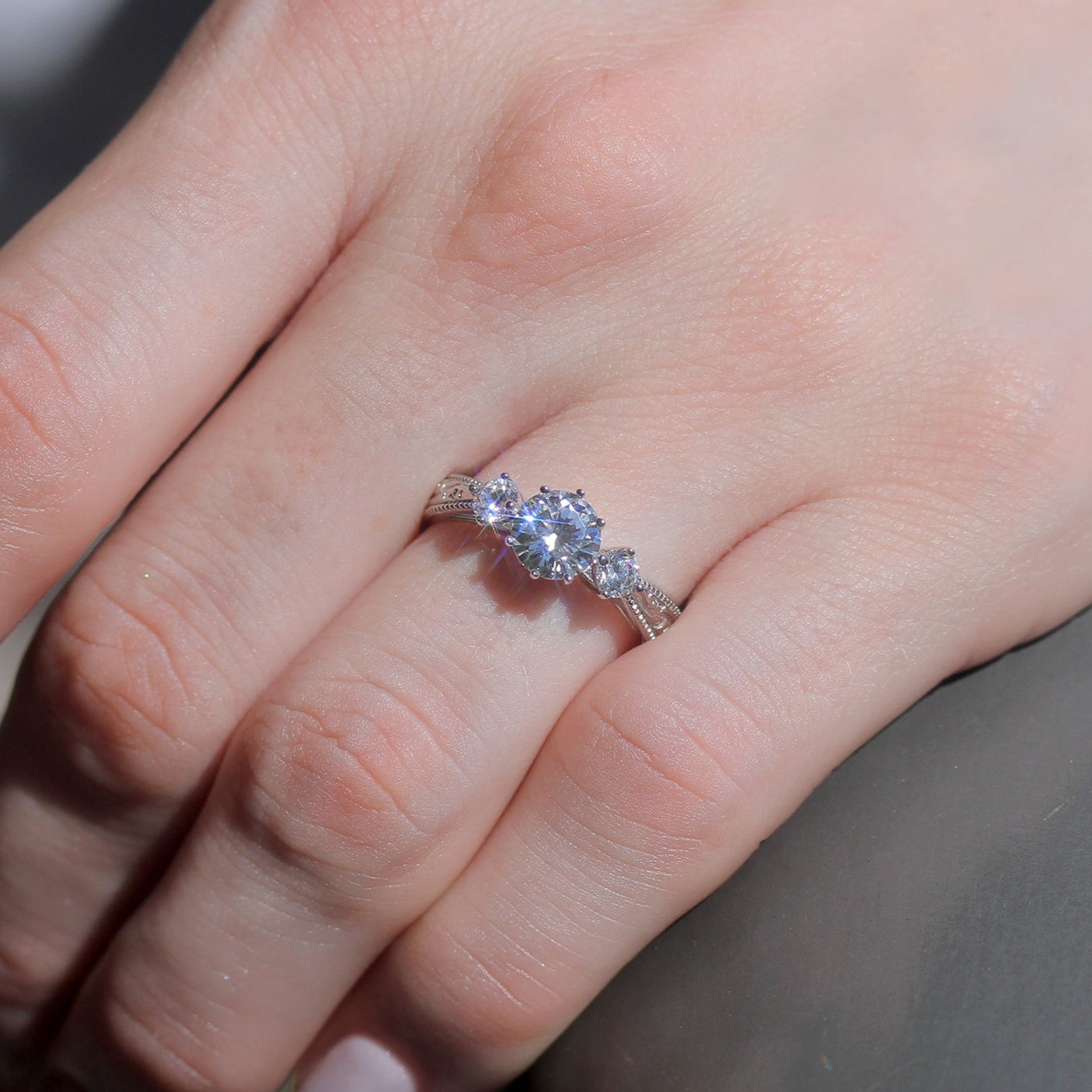 Close-up of a hand wearing a diamond ring with a blurred background