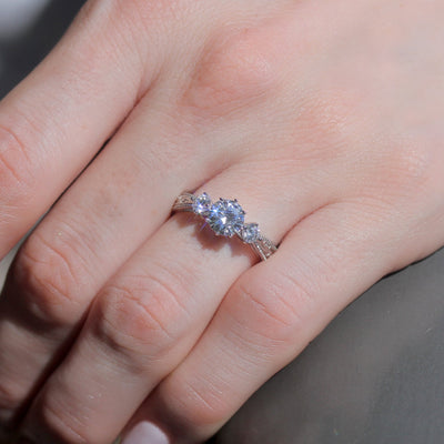 Close-up of a hand wearing a diamond ring with a blurred background
